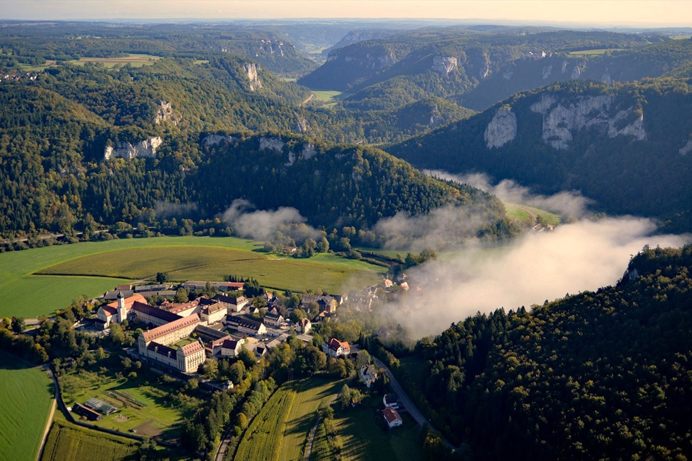 Steile Felsen säumen die noch junge Donau bei Beuron. Im Vordergrund das Benediktinerkloster Erzabtei St. Martin. © Reiner Enkelmann Steile Felsen säumen die noch junge Donau bei Beuron. Im Vordergrund das Benediktinerkloster Erzabtei St. Martin. © Reiner Enkelmann